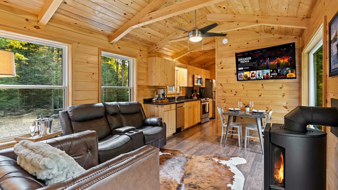 Living room of The Modern Pine: leather sofa, the Jøtul stove lit and the kitchen beyond